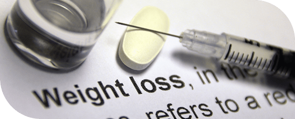Syringe, yellow pill, and glass vial arranged on a page of text defining weight loss.