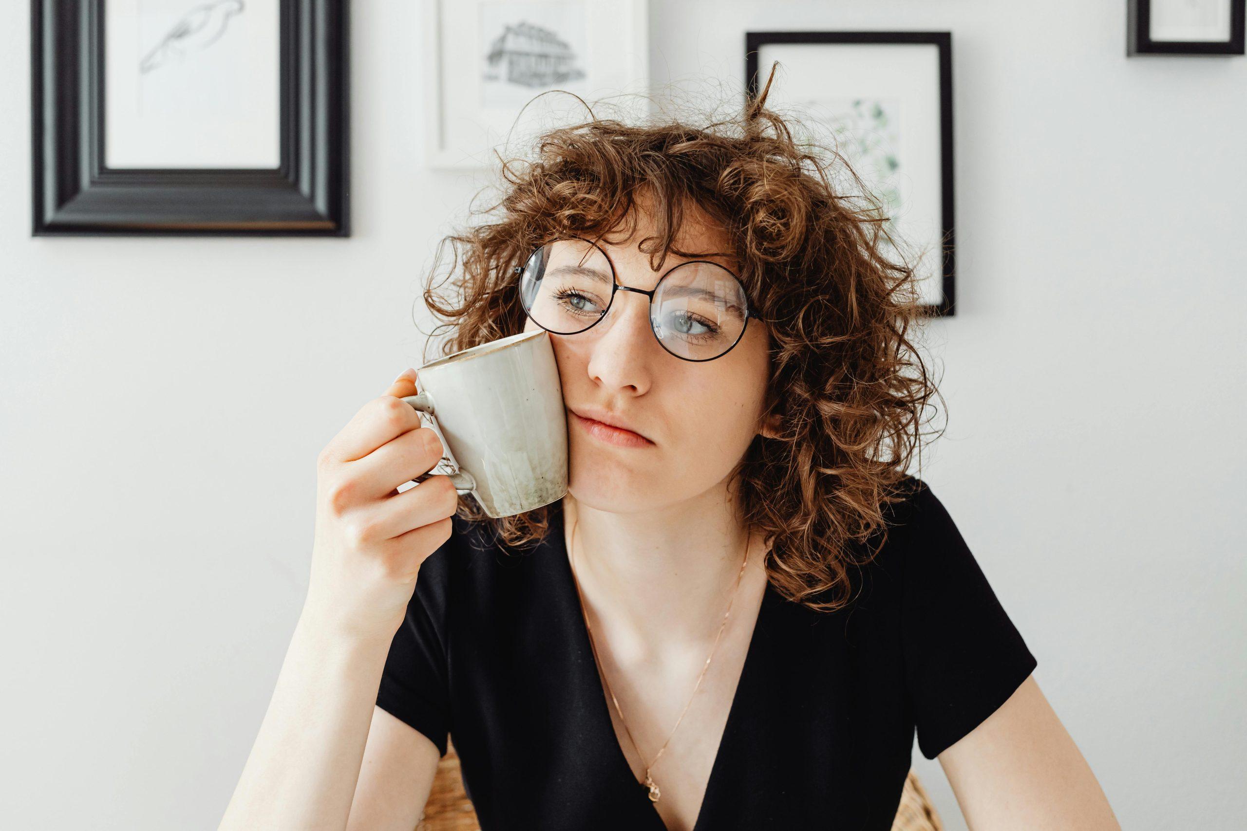 Woman holding a mug to her face, looking tired