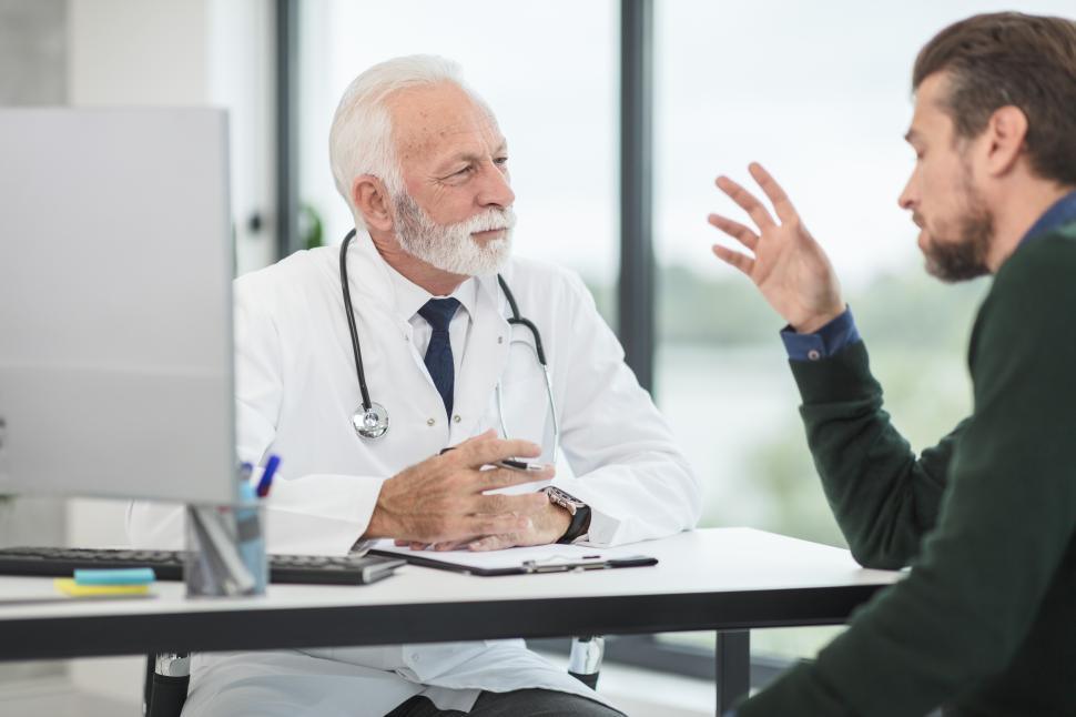 Male physician reviewing lab results and discussing testosterone therapy plan with middle-aged male patient in Chanhassen clinic