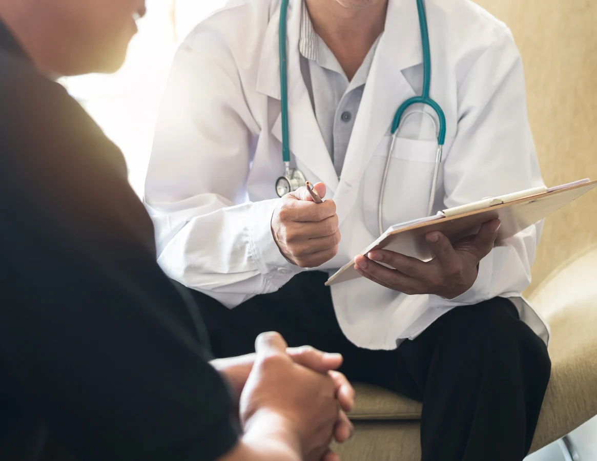 Male physician discussing testosterone therapy and fertility preservation options with younger male patient in Minneapolis clinic